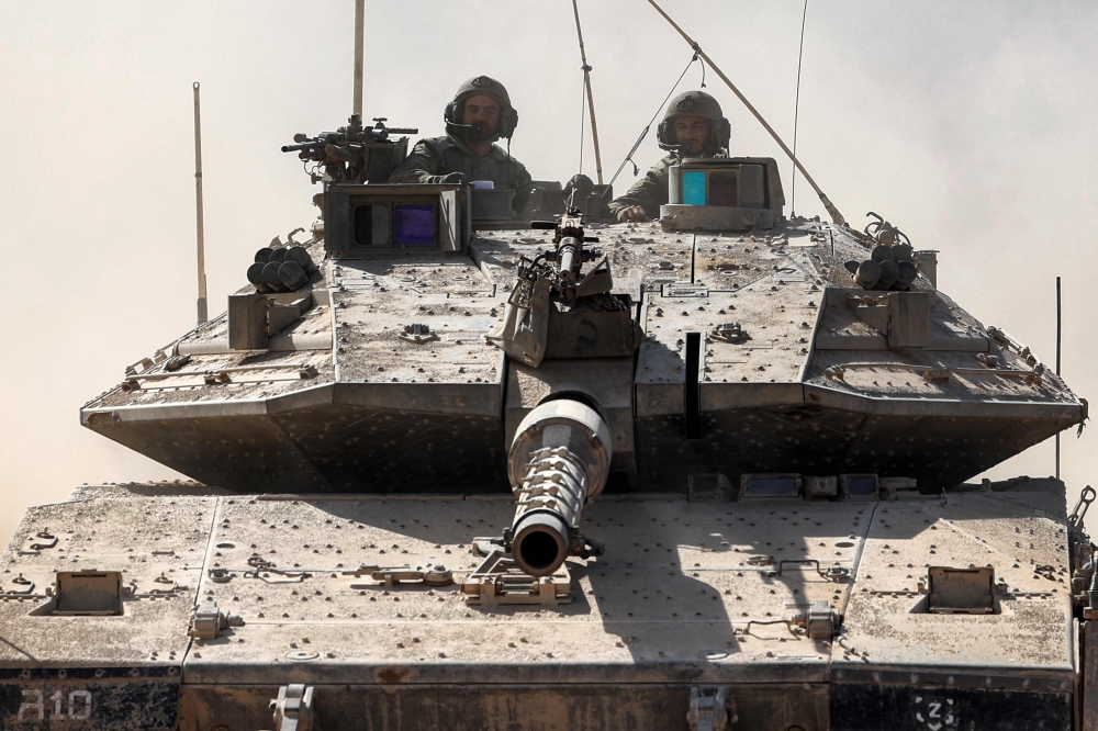 Israeli army soldiers ride in the turret of a Merkava battle tank deploying along the border with the Gaza Strip in southern Israel 