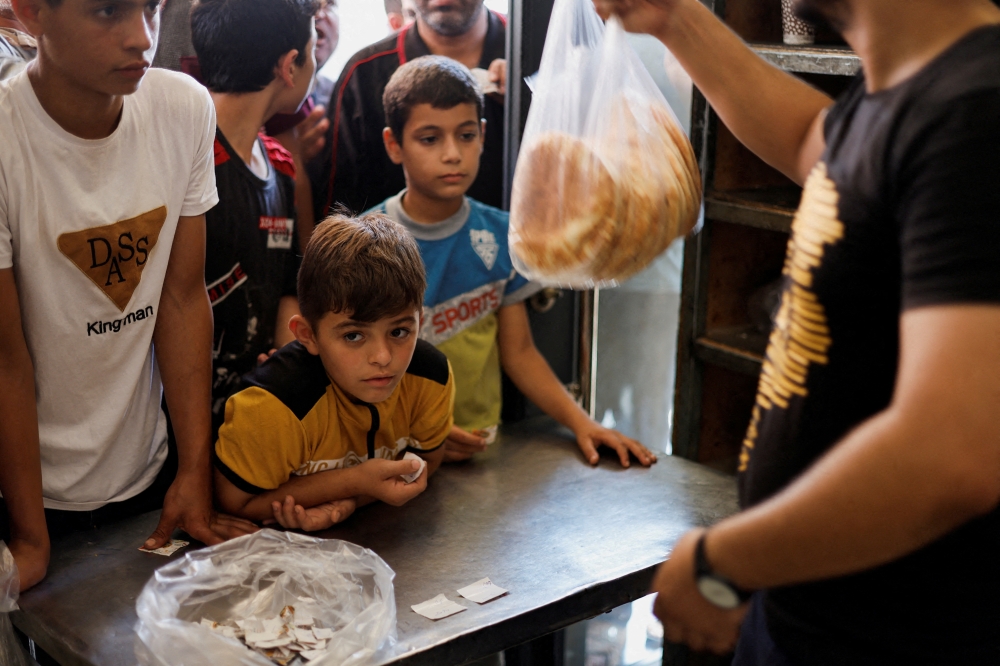 Palestinians wait to buy bread outside a bakery, amid the ongoing conflict between Israel and Hamas in Khan Younis in the southern Gaza Strip. - Reuters 