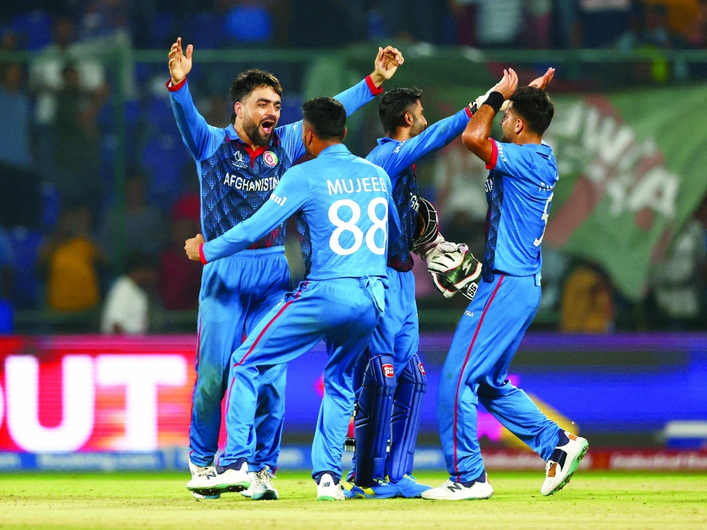 Afghanistan's Rashid Khan celebrates with Mujeeb Ur Rahman and teammates after taking the wicket of England's.—Reuters