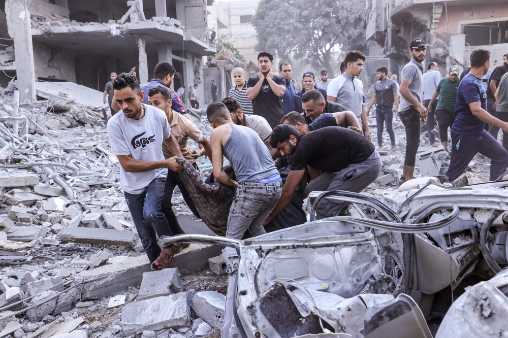 Palestinians evacuate a victim following an Israeli airstrike on Rafah on October 17