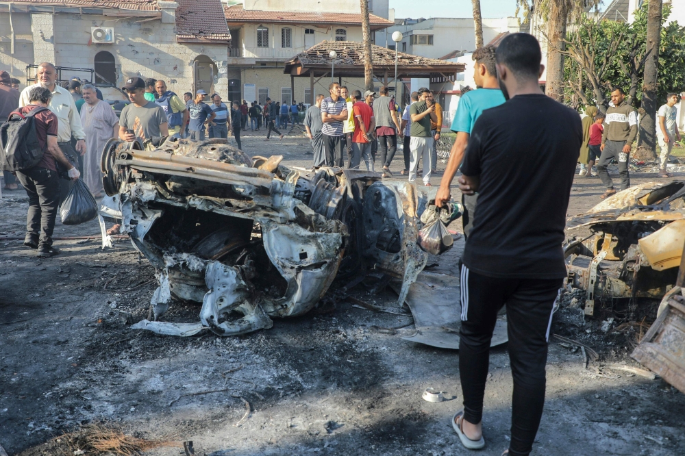 People inspect the damage at Ahli Arab hospital in central Gaza on October 18, 2023