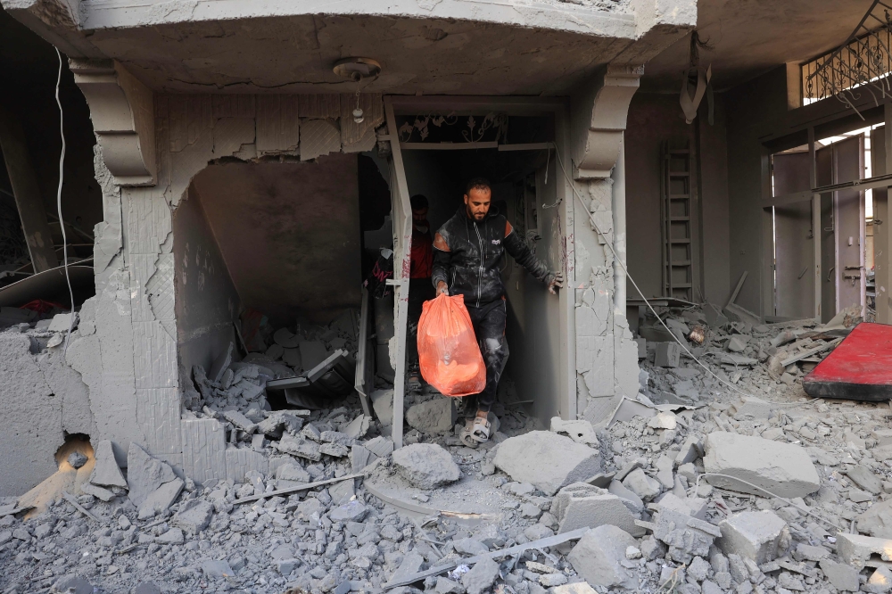 A Palestinian man salvages belongings from his destroyed home following Israeli bombardment in Rafah