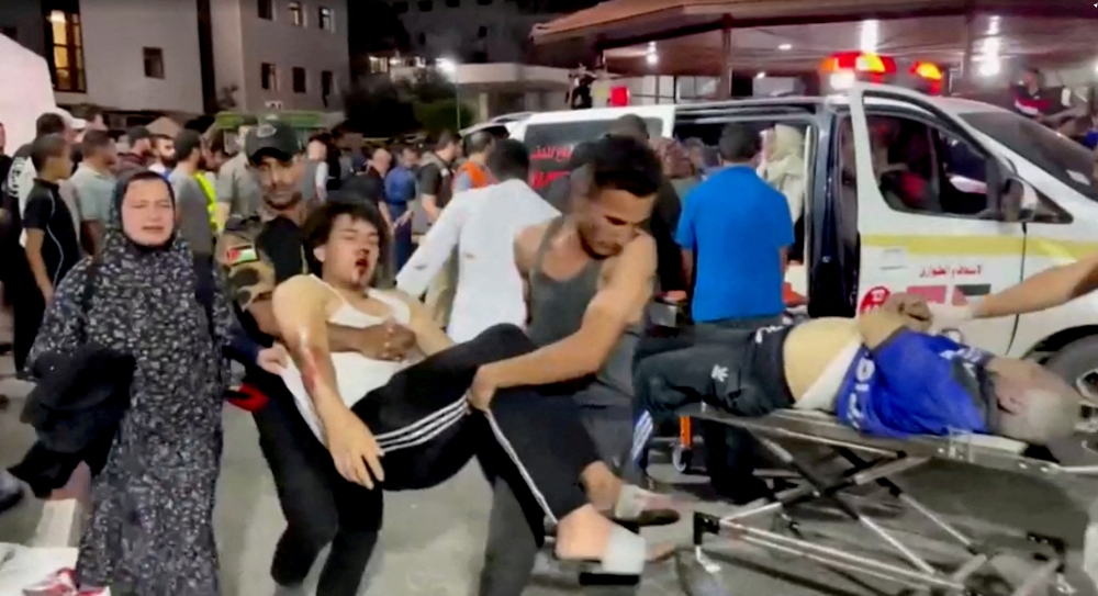 Injured people are taken into hospital after hundreds of Palestinians were killed in a blast at Al-Ahli hospital in Gaza that Israeli and Palestinian officials blamed on each other