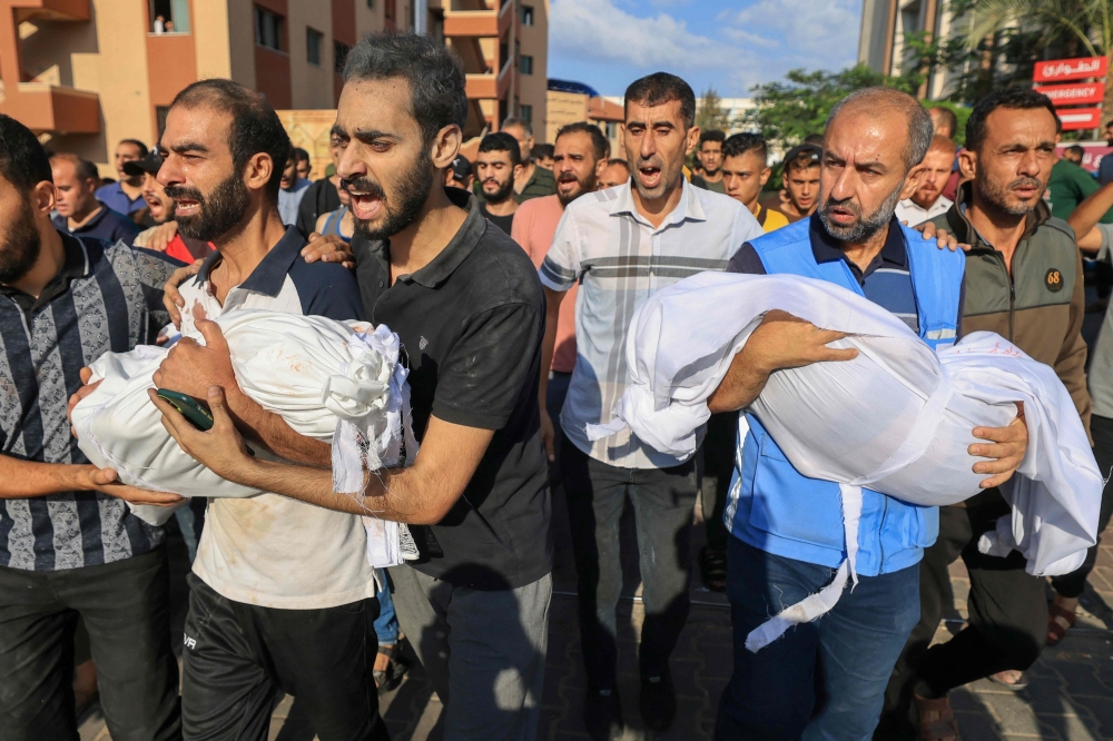 The fathers of children from the al-Majaida family killed when an Israeli air strike hit their home carry their bodies during their funeral in Khan Yunis
