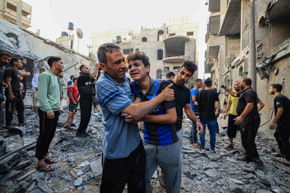 People react as Palestinian civil defence members and others search for survivors after an Israeli bombardment in Khan Yunis