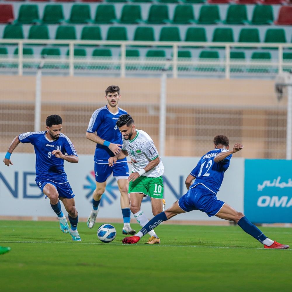 Al Nahda's Salah al Yahyai dribbles past Sur players.