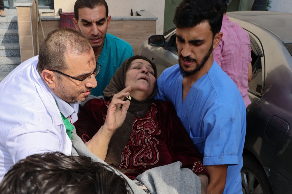 Medics carry a distressed woman outsid the Kuwait hospital, following an Israeli strike in Rafah in the southern Gaza Strip. — AFP 