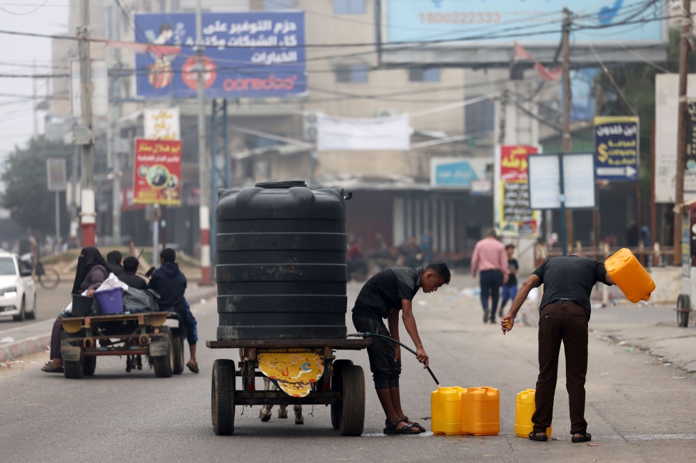 Men fill plastic jerricans with portable water in Rafah, in the southern Gaza Strip. — AFP 