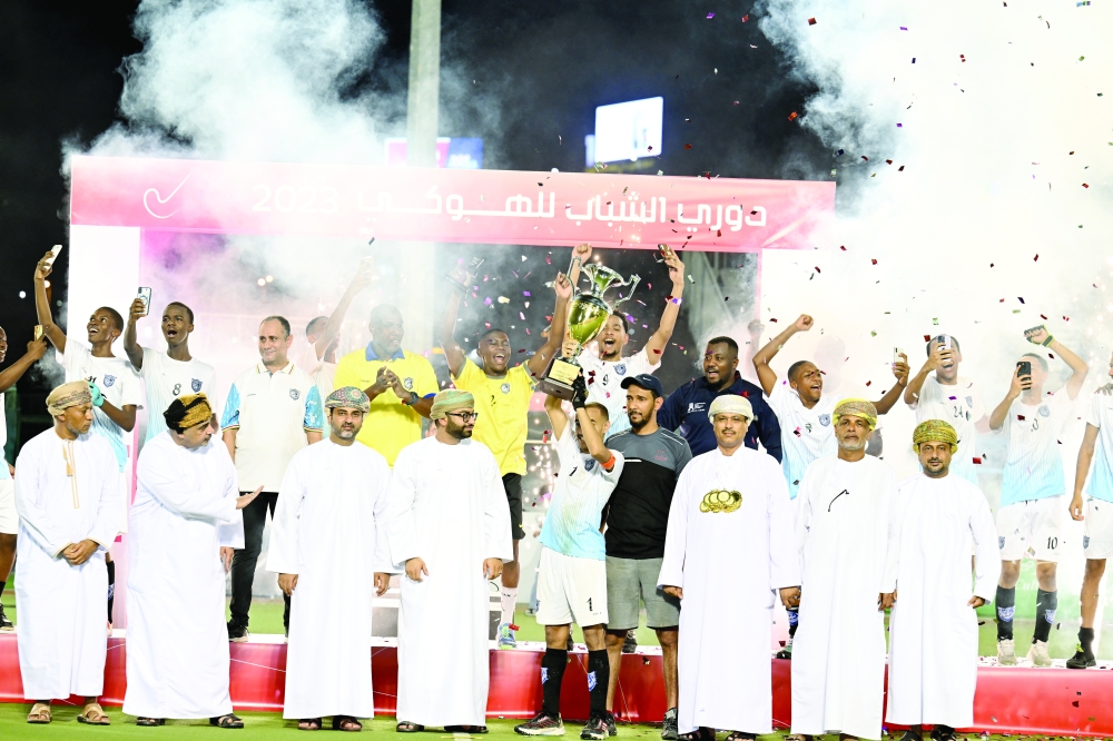 Salalah players celebrate with the trophy on the podium with officials. -- Saleh al Sharji