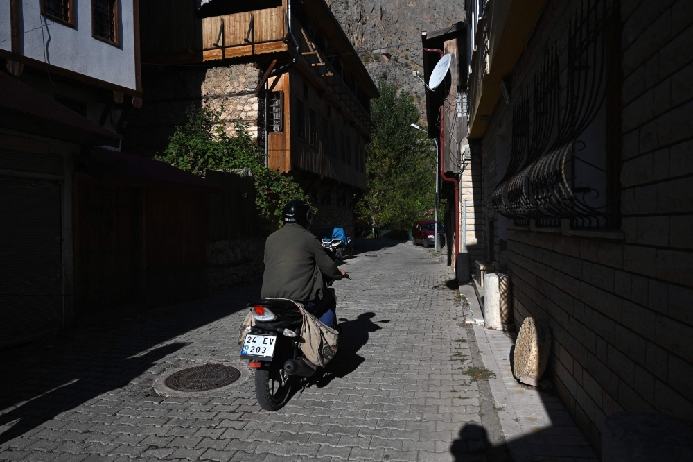 A man rides a motorcycle on a street in Kemaliye, eastern Turkey, on October 4, 2023. Founder of modern Turkey Mustafa Kemal Ataturk rewarded the loyalty of the Kemaliye town, nestled between the mountains and the sources of the Euphrates, by giving it his name ahead of creating the Turkish republic out of the ashes of the Ottoman Empire 100 years ago. (Photo by Ozan KOSE / AFP)


