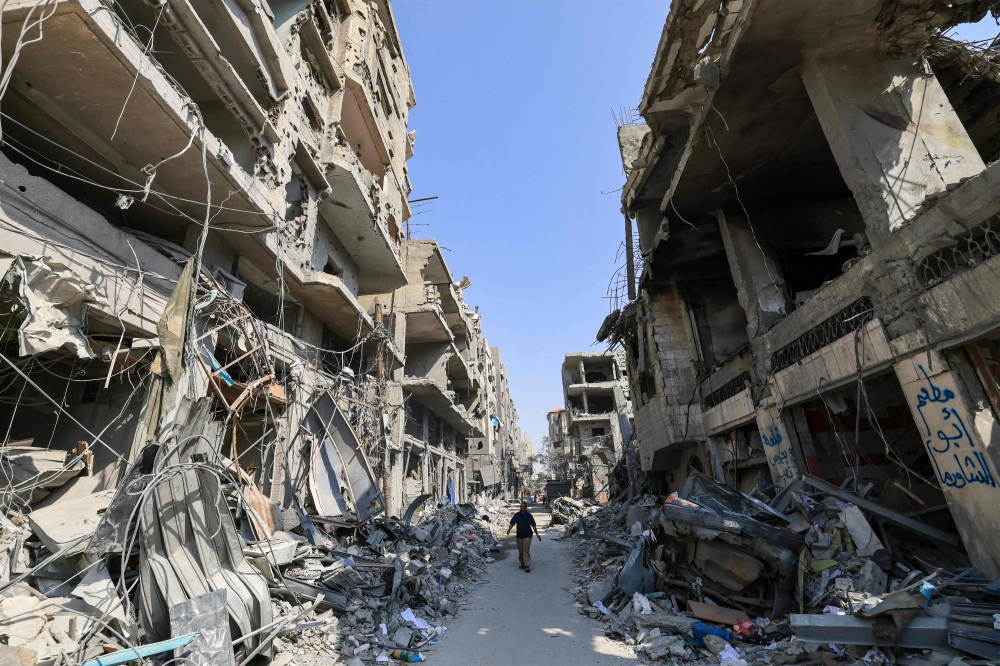 A Palestinian man walks amid the rubble of buildings hit in Israeli air strikes in Khan Yunis in the southern Gaza Strip. — AFP 