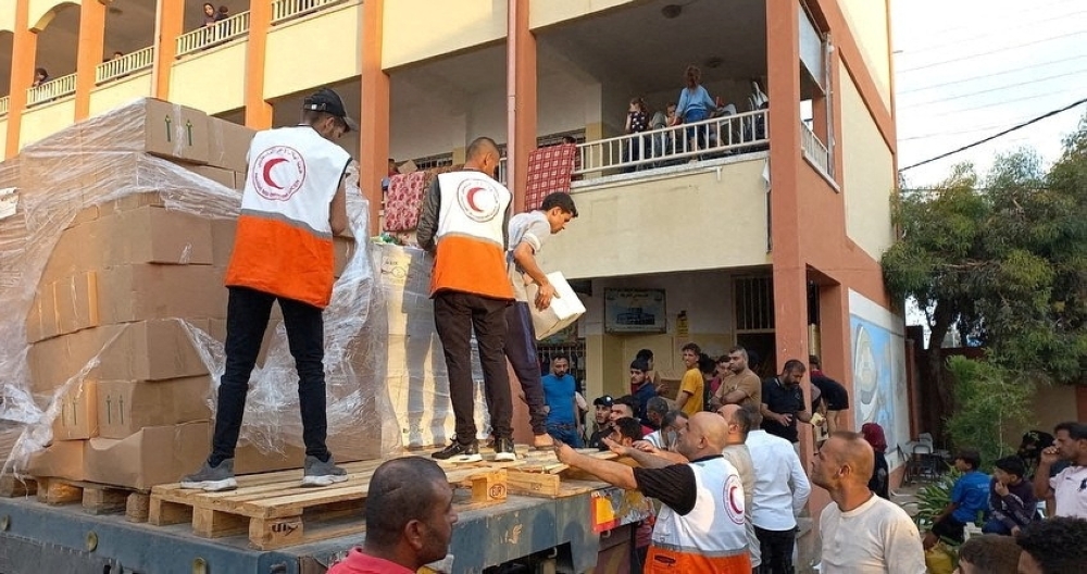 Members of the Palestine Red Crescent Society distribute aid to people in Deir al-Balah, in the central Gaza Strip