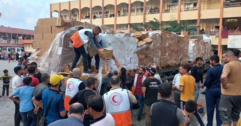 Members of the Palestine Red Crescent Society distribute aid to people in Deir al-Balah, in the central Gaza Strip