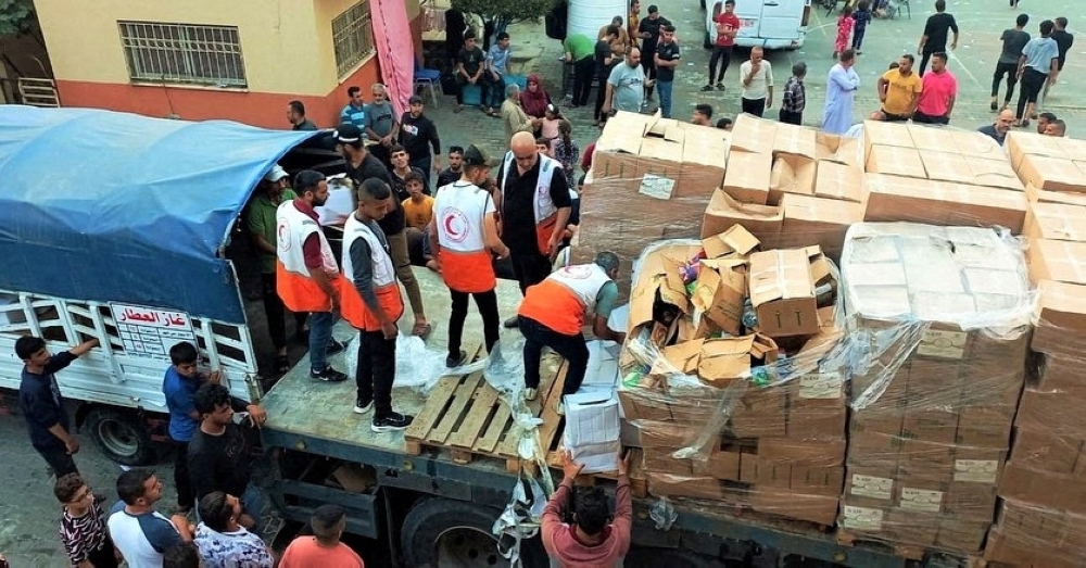 Members of the Palestine Red Crescent Society distribute aid to people in Deir al-Balah, in the central Gaza Strip, in this handout picture released on October 25, 2023.  Palestine Red Crescent Society/Handout via REUTERS    THIS IMAGE HAS BEEN SUPPLIED BY A THIRD PARTY. MANDATORY CREDIT. NO RESALES. NO ARCHIVES. BEST QUALITY AVAILABLE. REFILE - CORRECTING LOCATION FROM KHAN YOUNIS, IN THE SOUTHERN GAZA STRIP TO DEIR AL-BALAH, IN THE CENTRAL GAZA STRIP
