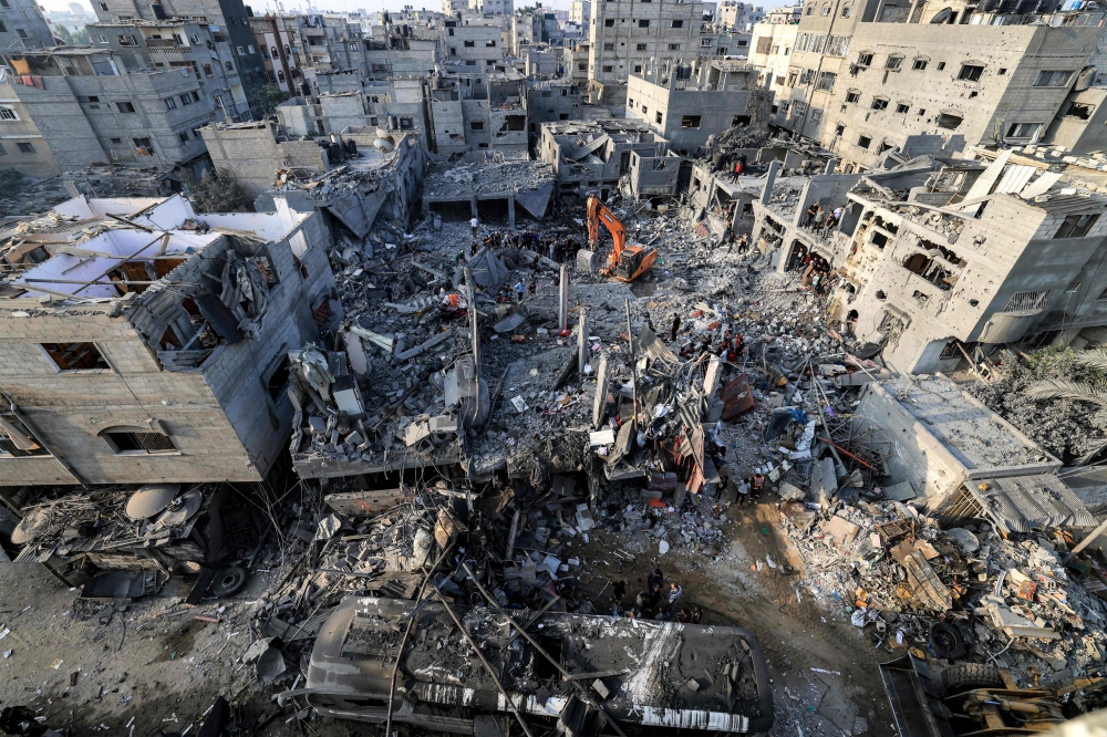 An excavator clears rubble as people search for survivors and the bodies of victims through buildings that were destroyed during Israeli bombardment, in Khan Yunis in the southern Gaza Strip on October 25, 2023. (Photo by Mahmud HAMS / AFP)

