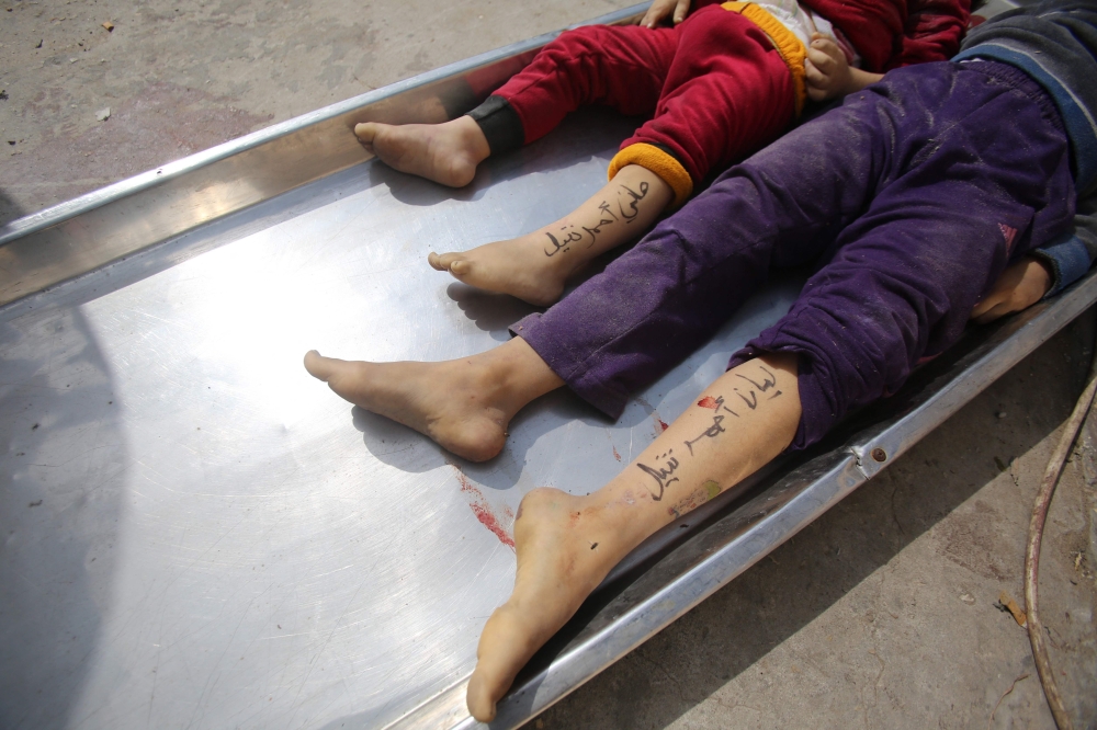 The bodies of children from the Nateel family, with their names Hani (L) and Layan written on their legs by their parents to help in identification