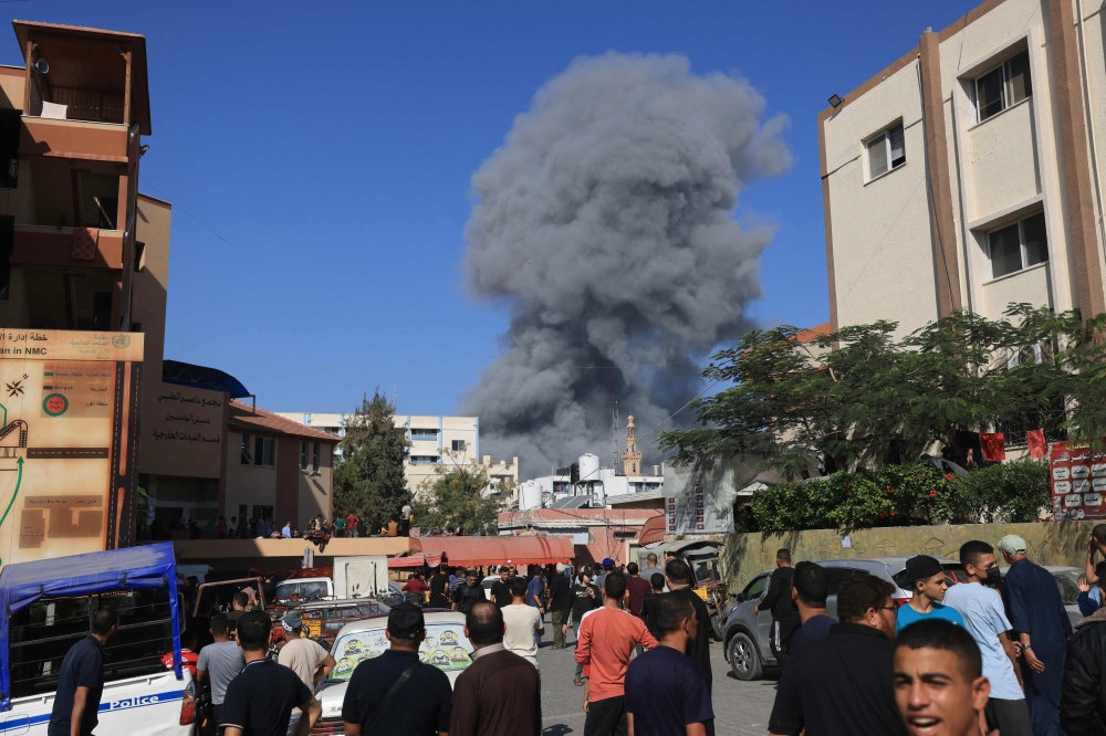 People watch as smoke and dust ascend following Israeli bombardment in Khan Yunis in the southern Gaza Strip. - AFP 