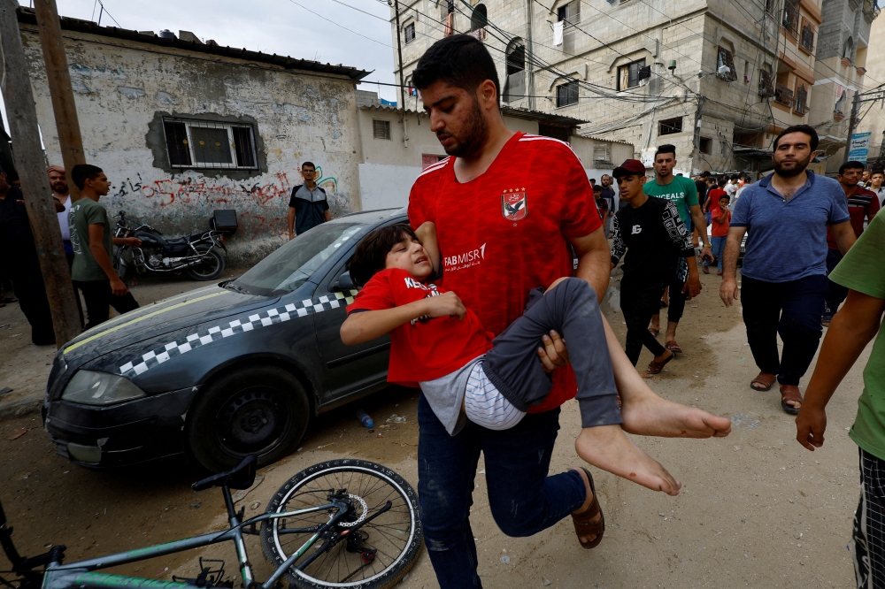 A man carries a child at the site of an Israeli air strike on a house  in the southern Gaza Strip