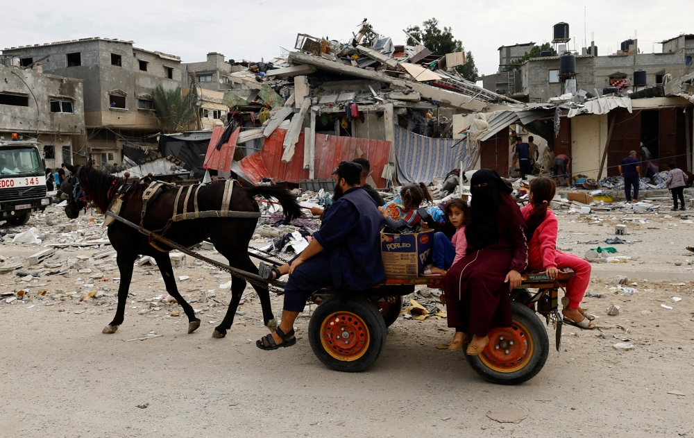 Palestinians ride a horse-drawn wagon next to the site of an Israeli air strike on a house