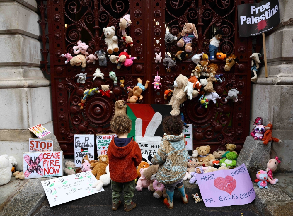 Children place teddy bears in solidarity with children in the besieged Palestinian enclave of Gaza, outside the Foreign and Commonwealth Office in London. - Reuters
