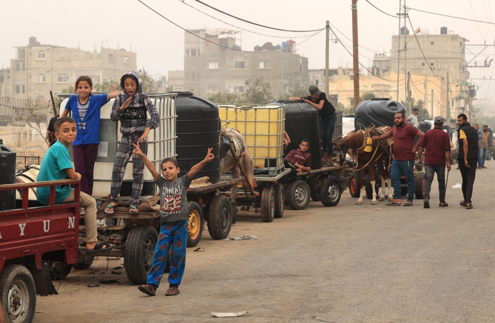 Palestinian civilians wait to collect water using carts, in Rafah in the southern Gaza Strip