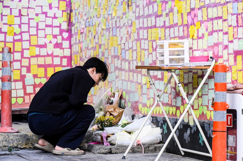 A man looks at flowers and notes left in memory of victims of the October 29, 2022 crowd crush that killed more than 150 people during Halloween celebrations, at the site of the tragedy in the popular Itaewon nightlife area in Seoul on October 25, 2023. (Photo by ANTHONY WALLACE / AFP)

