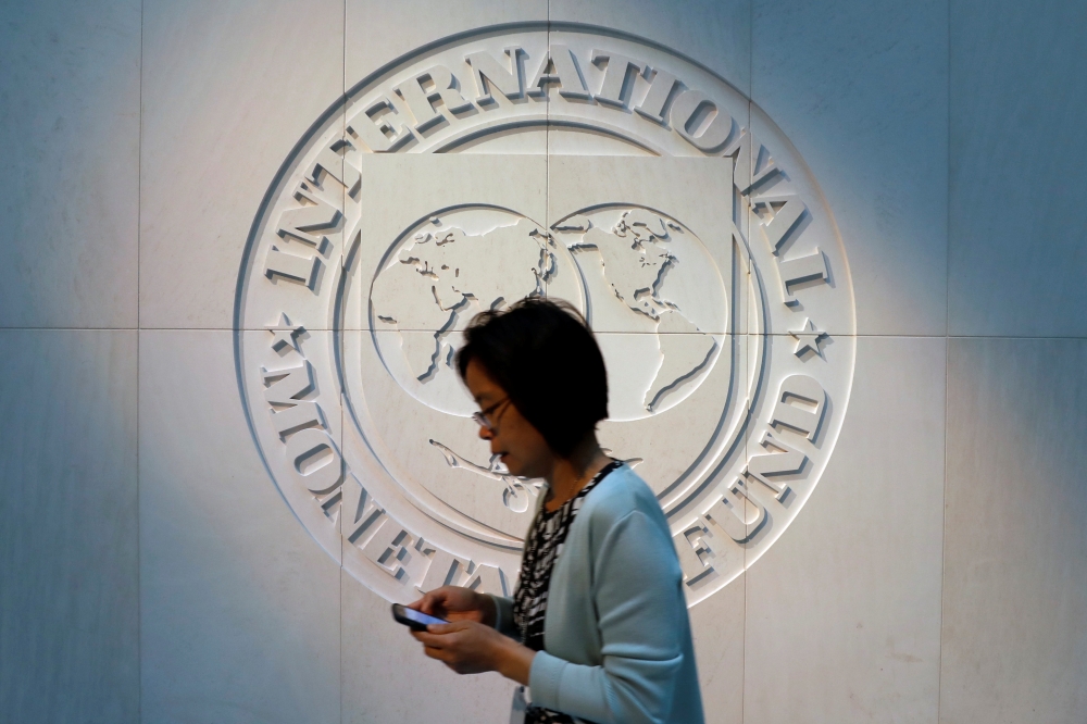 A woman walks past the IMF logo at its headquarters in Washington. — Reuters