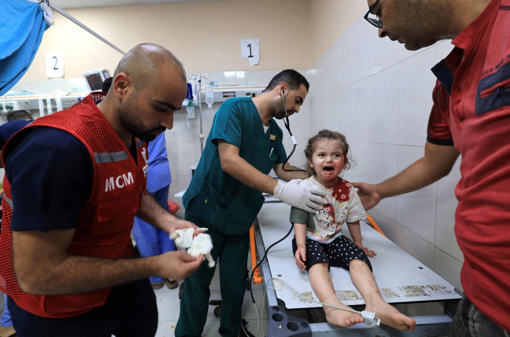 Palestinian nurse arrives to attend to a little girl with a head wound at the Nasser hospital following Israeli bombardment of Khan Yunis. — AFP 