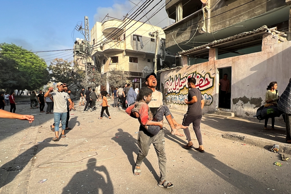 A Palestinian carries a child casualty near the site of Israeli strikes on houses, in Gaza City. — Reuters 