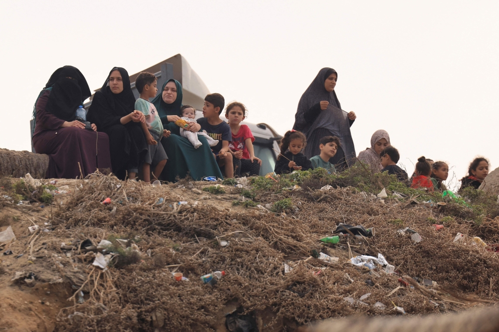 Palestinian women and children sit along the sea front in Deir el-Balah in the southern Gaza Strip on October 29, 2023, amid the ongoing battles between Israel and the Palestinian group Hamas. Thousands of civilians, both Palestinians and Israelis, have died since October 7, 2023, after Palestinian Hamas militants based in the Gaza Strip entered southern Israel in an unprecedented attack triggering a war declared by Israel on Hamas with retaliatory bombings on Gaza. (Photo by MAHMUD HAMS / AFP)

