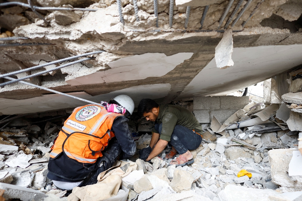 An Emergency worker and a Palestinian man check the damage at the site of Israeli strikes on houses, in Khan Younis. — Reuters 