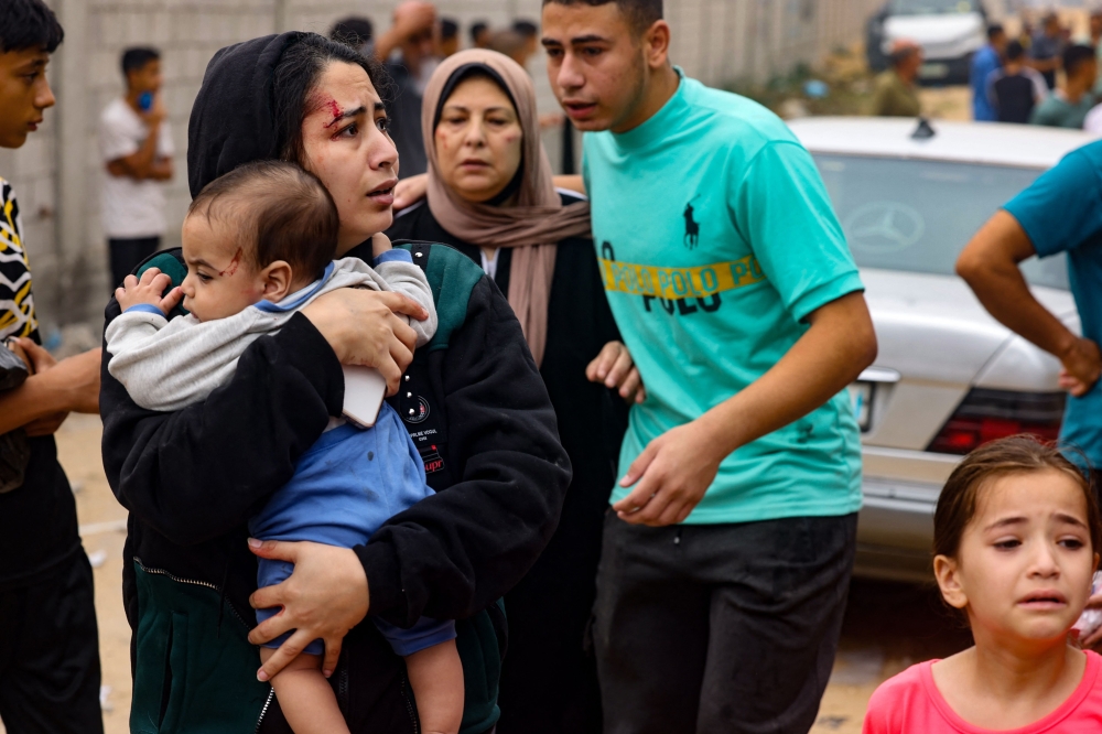 An injured woman carries a baby in the aftermath of Israeli bombing in Rafah in the southern Gaza Strip 