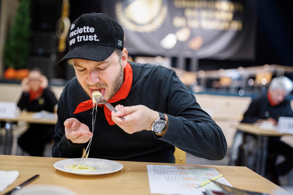 A member of the jury samples a raclette during the first-ever Raclette World Championships featuring local and international raclette cheeses, in Morgins, on October 28, 2023. Up in the Swiss Alps, the air hangs thick with the funk of hot cheese as the planet's best melt away the competition at the inaugural Raclette World Championships. The Swiss native dish dates back centuries to a time when mountain herdsmen would heat their cheese on an open fire and scrape off the melted part to keep them going. (Photo by VALENTIN FLAURAUD / AFP)

