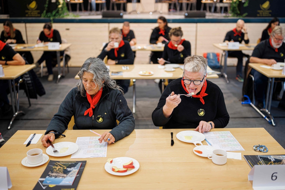 Members of the jury sample and grade raclettes during the first-ever Raclette World Championships featuring local and international raclette cheeses, in Morgins, on October 28, 2023. Up in the Swiss Alps, the air hangs thick with the funk of hot cheese as the planet's best melt away the competition at the inaugural Raclette World Championships. The Swiss native dish dates back centuries to a time when mountain herdsmen would heat their cheese on an open fire and scrape off the melted part to keep them going. (Photo by VALENTIN FLAURAUD / AFP)


