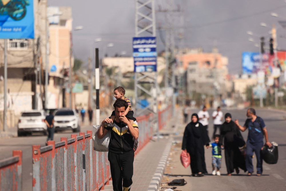 Palestinians carrying belongings walk on a road as they flee the Nuseirat refugee camp, in the central Gaza Strip on October 30, 2023, amid the ongoing battles between Israel and the Palestinian group Hamas. (Photo by MAHMUD HAMS / AFP)

