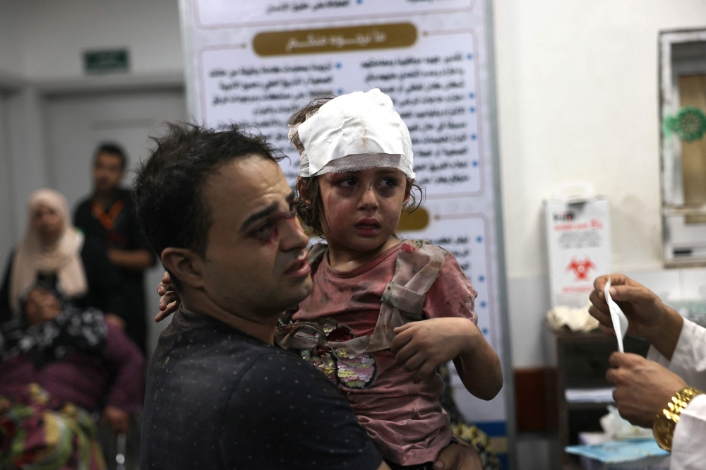 A Palestinian man carries his injued daughter at the Najjar hospital following an Israeli air strike on a home in Rafah, in the southern Gaza Strip on October 30 , 2023, amid the ongoing battles between Israel and the Palestinian group Hamas. Thousands of civilians, both Palestinians and Israelis, have died since October 7, 2023, after Palestinian Hamas militants based in the Gaza Strip entered southern Israel in an unprecedented attack triggering a war declared by Israel on Hamas with retaliatory bombings on Gaza. (Photo by SAID KHATIB / AFP)

