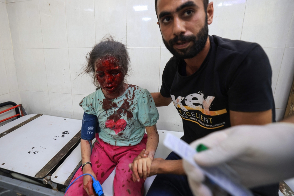A Palestinian man sits with an injured girl 