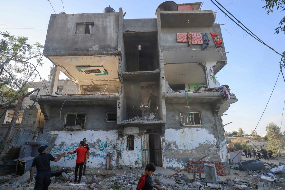 Palestinians search a damaged building following Israeli strikes in Khan Yunis in the southern Gaza Strip 
