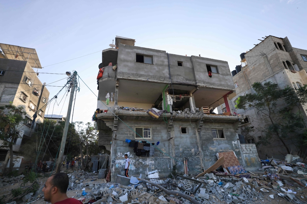 Palestinians search a damaged building following Israeli strikes in Khan Yunis 