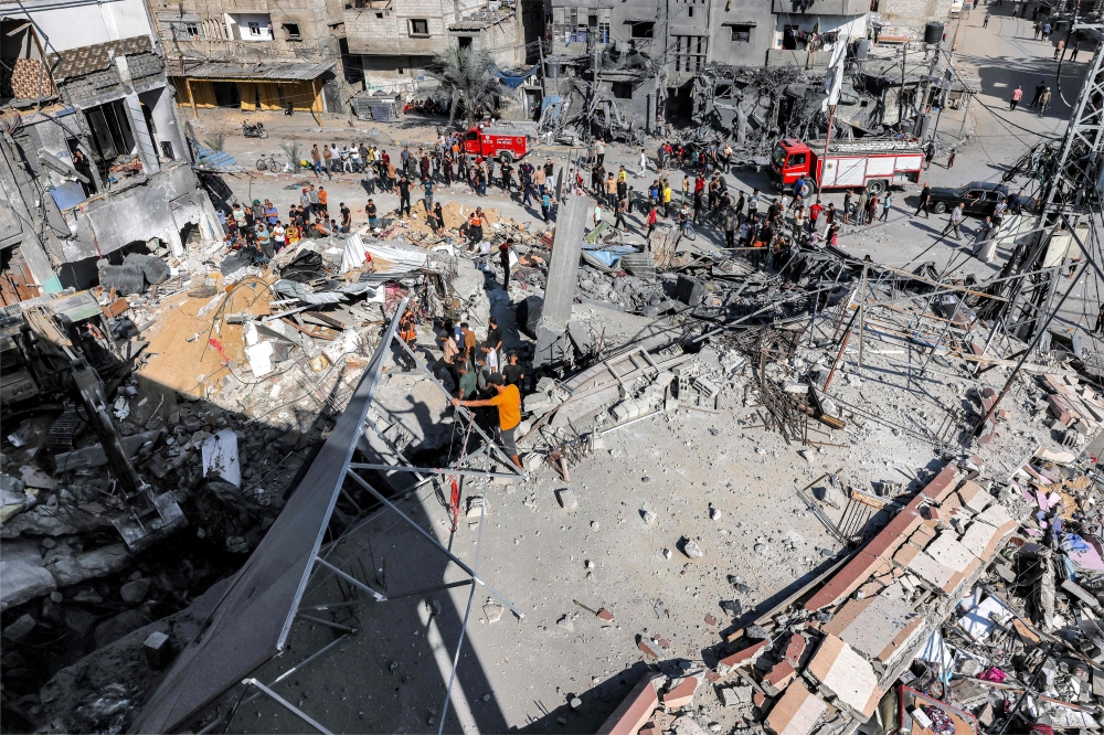 People stand by as civil defence workers search for victims and survivors in the rubble of a building that was hit by Israeli bombardment in Rafah in southern Gaza. — AFP 