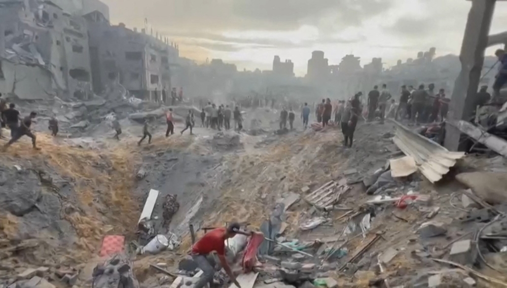  Palestinians looking for survivors in a crater following an Israeli strike on a refugee camp in Jabalia on the southern Gaza Strip