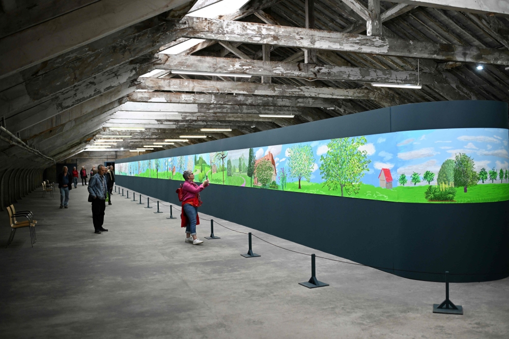 Members of the public view an artwork by David Hockney in Salts Mill, a former textile mill, now an art gallery, shopping centre, restaurant and commercial space in Saltaire, near Bradford, on October 13, 2023.  Once the epicentre of global trade, the awe-inspiring buildings of northern England's industrial age have capitalised on the vision and ambition of their creators to reinvent themselves as world-renowned cultural and economic hubs. Inspired by Renaissance figures such as the  Medici family, the textile titans of 18th and 19th century Britain built monumental structures designed to stand "forever" as a testament to their power and tastes. - TO GO WITH AFP STORY by James PHEBY
 (Photo by Oli SCARFF / AFP) / TO GO WITH AFP STORY by James PHEBY


