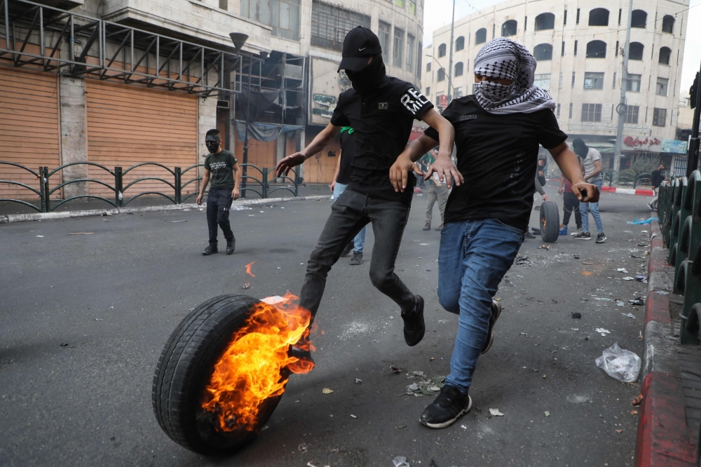 TOPSHOT - Palestinian protesters burn tyres amid clashes with Israeli security forces following a demonstration in Hebron in the occupied West Bank, on November 1, 2023, in support of Palestinians of the Gaza Strip amid ongoing battles between Israel and the Hamas movement. (Photo by MOSAB SHAWER / AFP)

