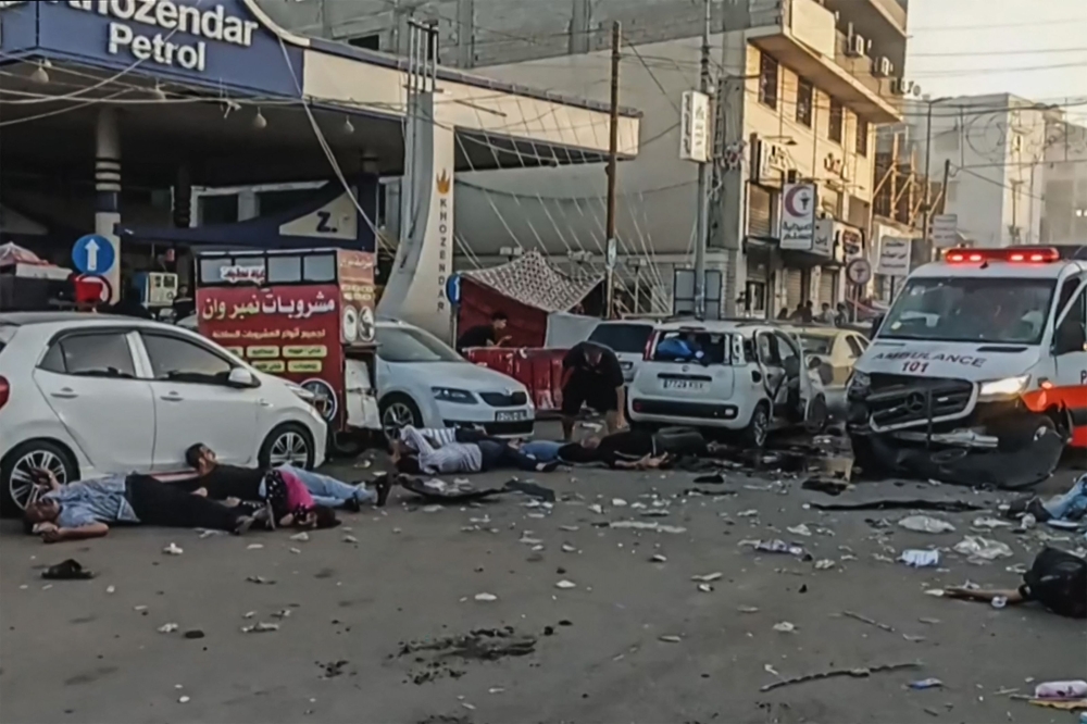 Victims lying near an ambulance damaged in a reported Israeli strike in front of Al-Shifa hospital in Gaza City 