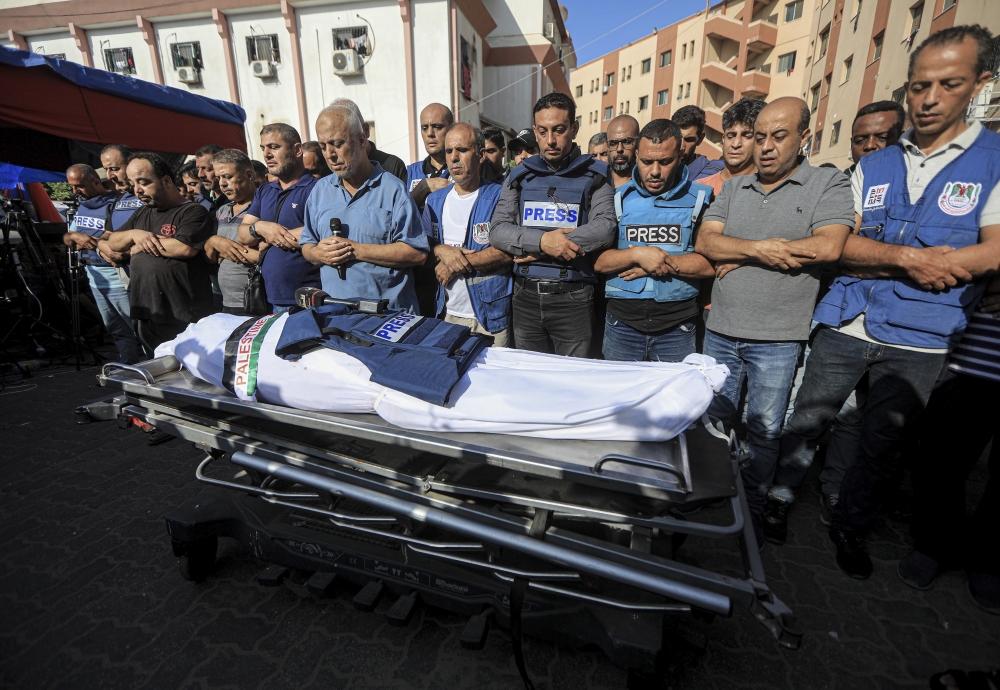 Fellow journalists mourn over the body of Palestinian TV journalist Mohammed Abu Hatab, who was killed along with eleven of his family members when their home was hit by an Israeli bombardment, in Khan Younis in the southern Gaza Strip, on Friday, Nov. 3,