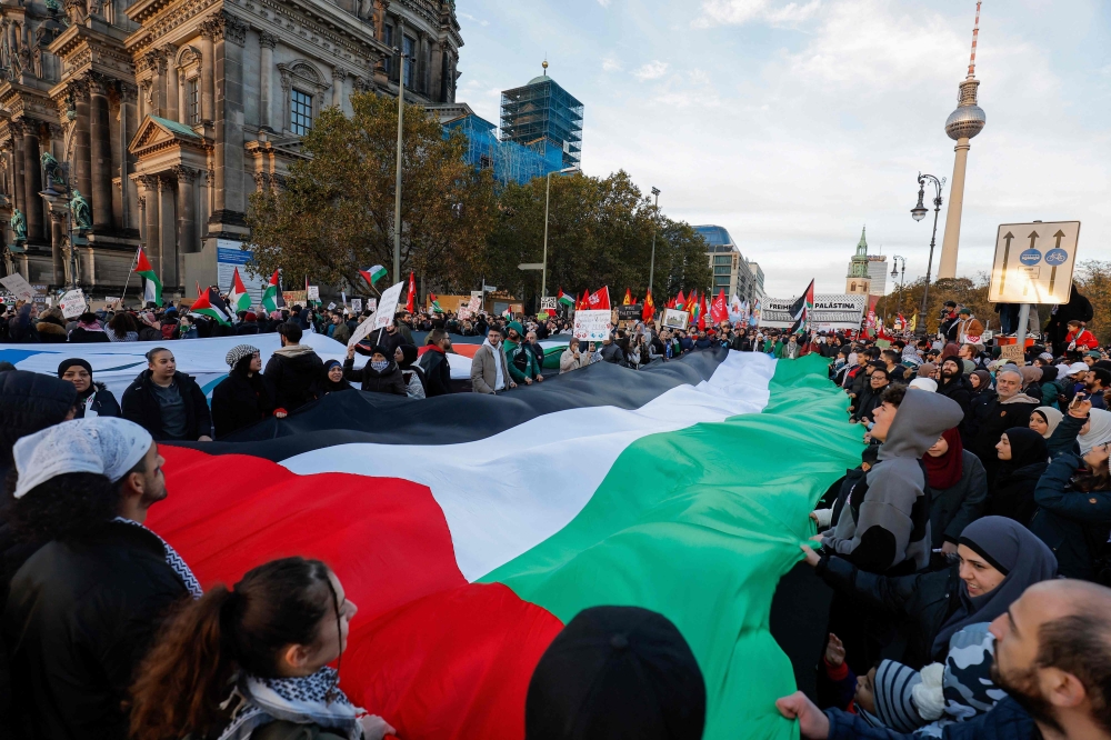 Demonstrators carry a giant Palestinian flag during a protest in support of Palestinians under the slogan 'Free Palestine' with the TV Tower in the background in Berlin. - AFP
