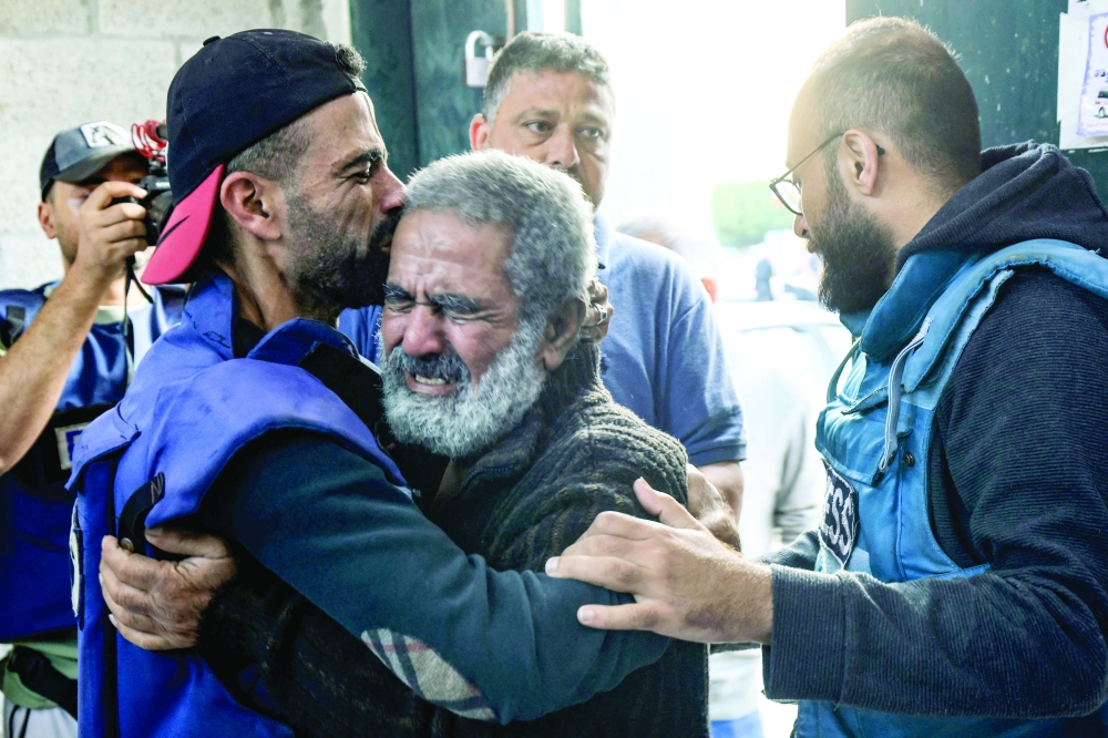 Palestinian cameraman hugs his father after two of his children and his brother were killed in an Israeli strike on the Al-Maghazi refugee camp in Deir Balah. — AFP