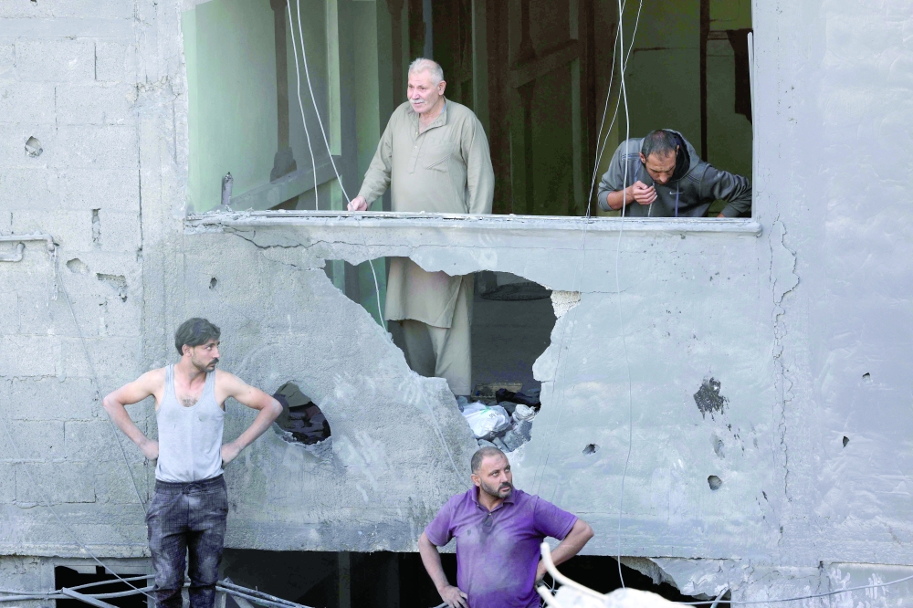 People stare from a damaged building at the destruction caused by an Israeli strike in the Al Maghazi refugee camp in Deir Balah in the central Gaza Strip, on Sunday. — AFP