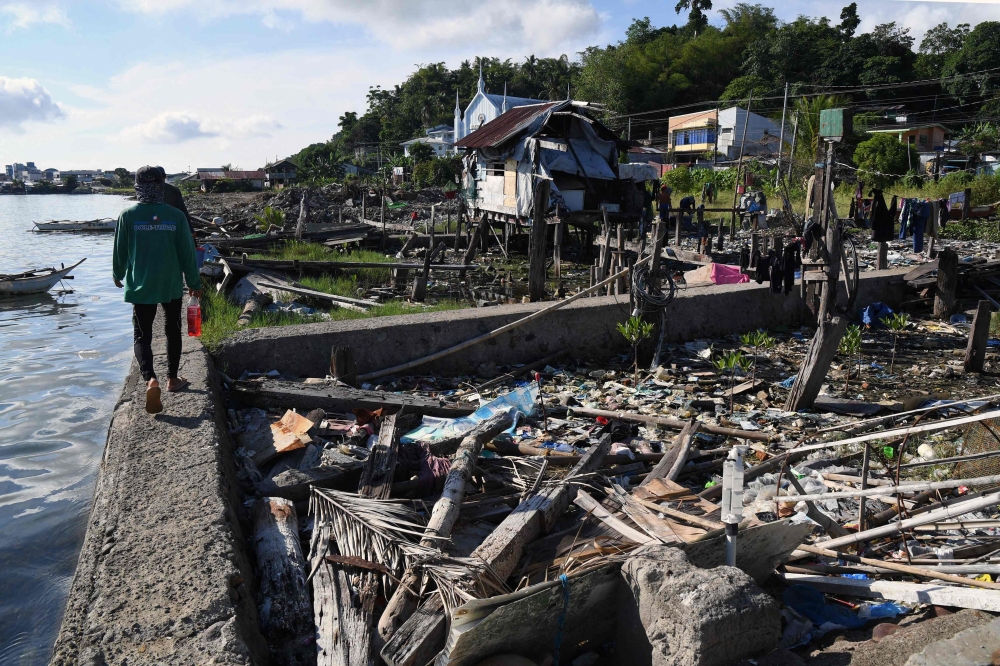 A person walking past debris on waterfront plots where houses once stood before Super Typhoon Haiyan struck in 2013, in Tacloban City, Leyte province