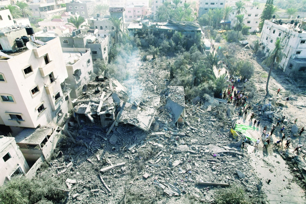 Palestinians gather at the site of an Israeli strike on a house, in Deir Al-Balah, in central Gaza Strip. — Reuters 